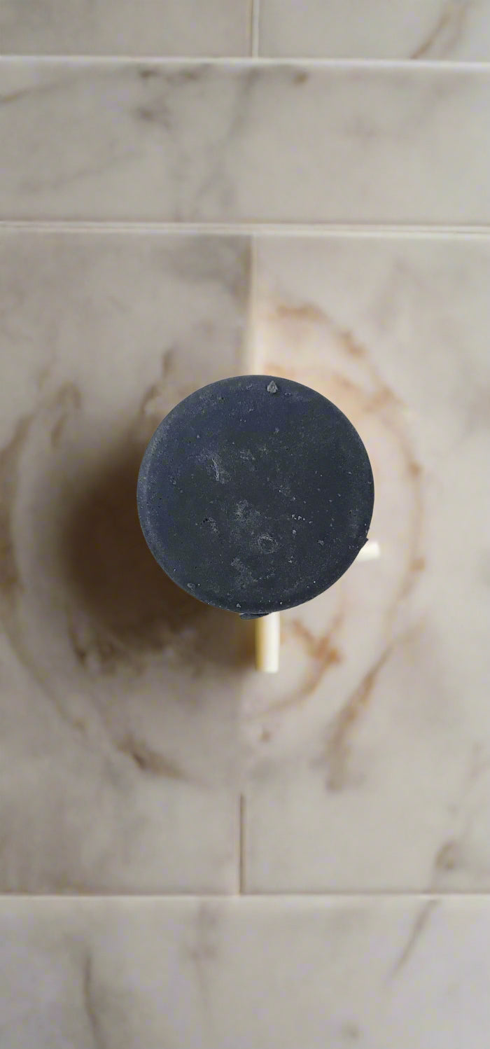 Black circular object on a white surface with a wooden edge.
